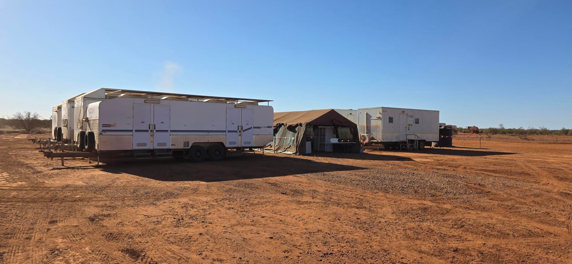 Portable site trailers and field camp setup in a remote desert worksite.
