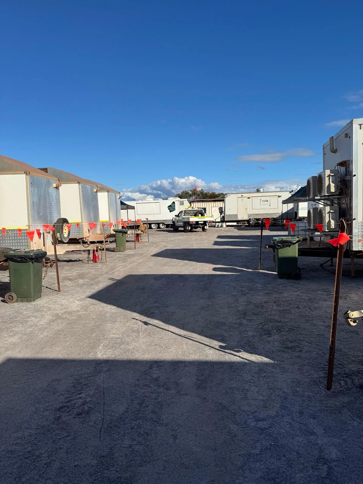 Temporary site compound with portable site offices, trailers, and utility vehicles on a gravel yard.
