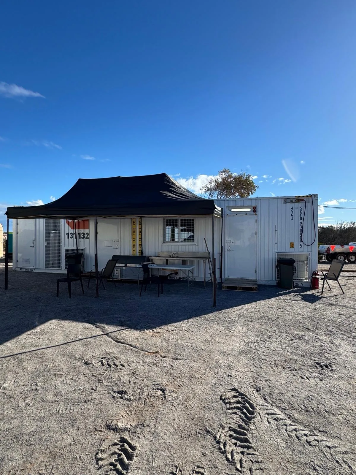Caravan Camps setting up with desks and chairs under a black tent top