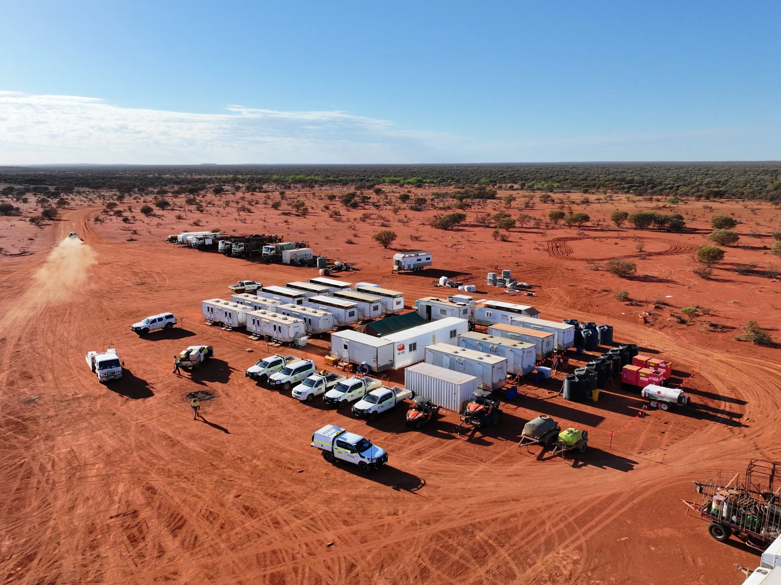 Remote mining site camp with portable buildings, vehicles, and equipment in a desert landscape.